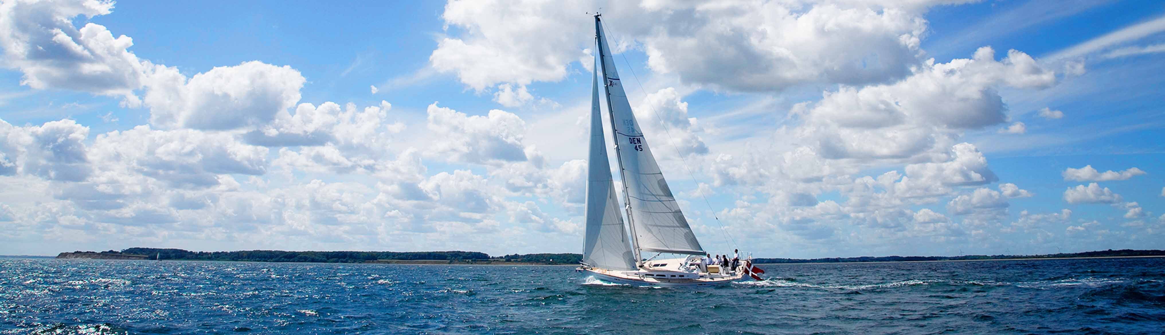 Segelyacht mit gesetztem Großsegel und Crew an Bord...